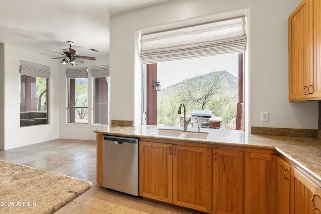 kitchen with ceiling fan, brown cabinetry, visible vents, stainless steel dishwasher, and a sink