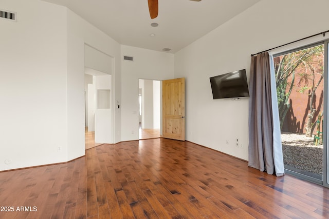 interior space featuring a towering ceiling, ceiling fan, wood finished floors, and visible vents