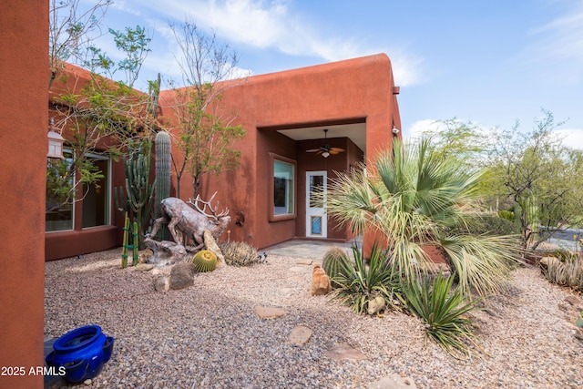 entrance to property featuring ceiling fan and stucco siding