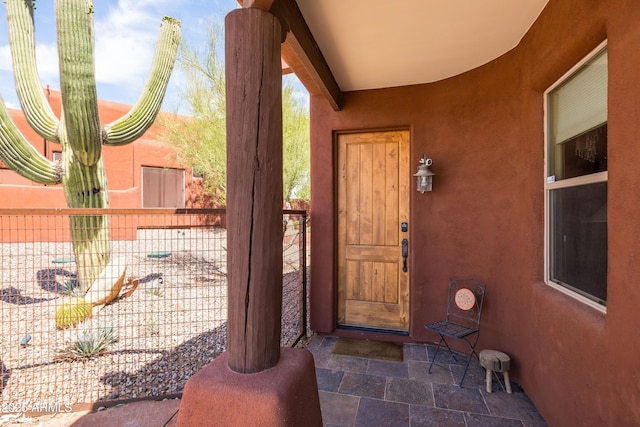 doorway to property featuring fence and stucco siding