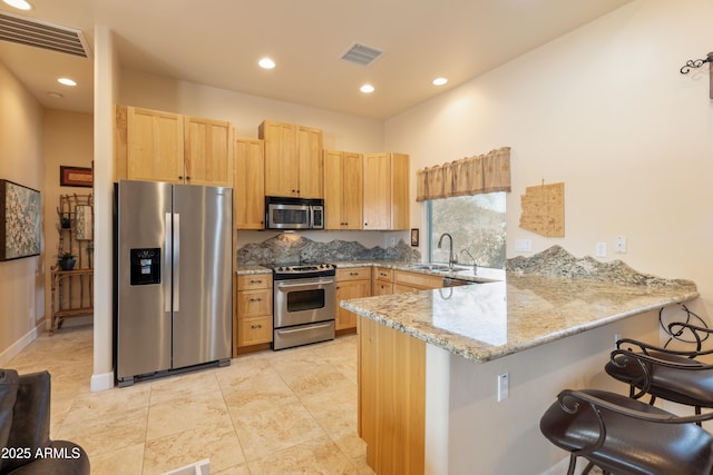 kitchen with stainless steel appliances, visible vents, a peninsula, and light brown cabinets