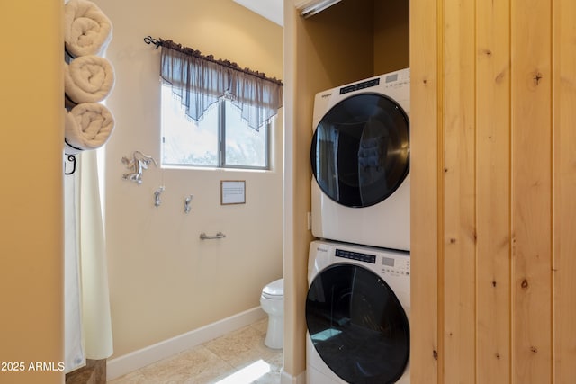 clothes washing area with baseboards, tile patterned flooring, laundry area, and stacked washer / dryer