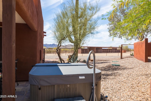 view of yard featuring a hot tub, fence, and a mountain view
