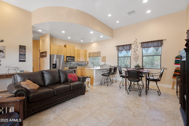 living room with recessed lighting, arched walkways, visible vents, and baseboards