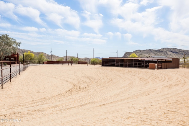 view of community featuring an exterior structure, an enclosed area, a mountain view, and an outbuilding