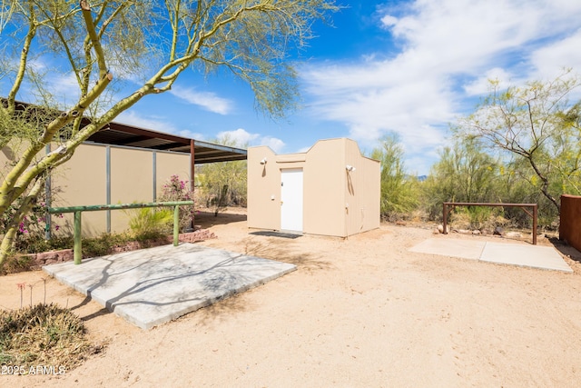 rear view of property with a storage shed, an outbuilding, and stucco siding