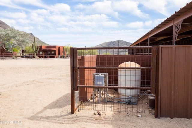 view of gate with an outbuilding, a mountain view, and an exterior structure