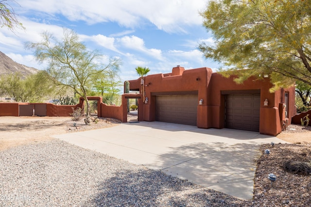 view of front facade with a garage, fence, stucco siding, and driveway