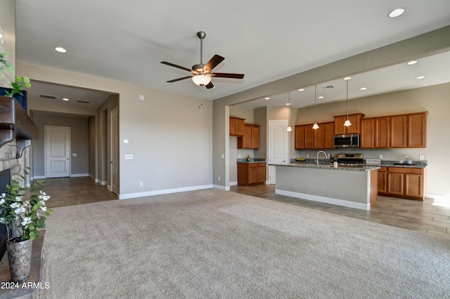 unfurnished living room featuring ceiling fan, a stone fireplace, sink, and light carpet