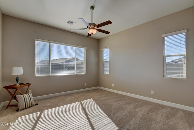 carpeted empty room featuring ceiling fan and a wealth of natural light