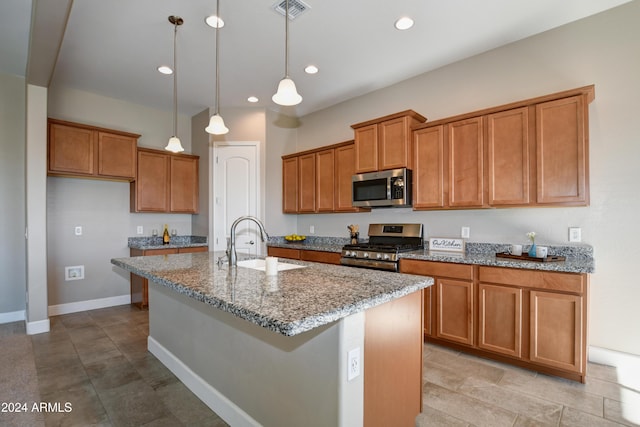 kitchen featuring stone counters, sink, hanging light fixtures, a kitchen island with sink, and appliances with stainless steel finishes