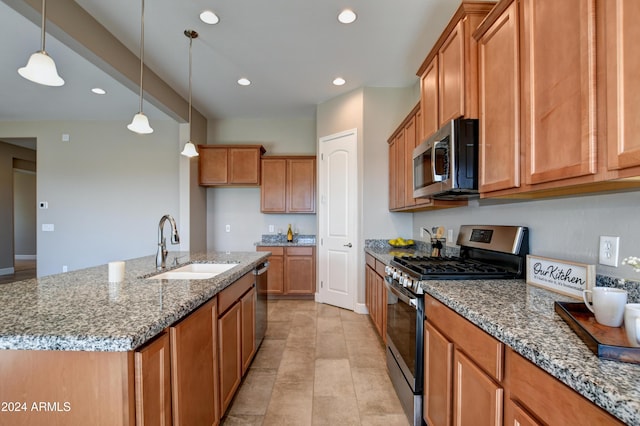 kitchen with stainless steel appliances, a kitchen island with sink, sink, pendant lighting, and stone countertops