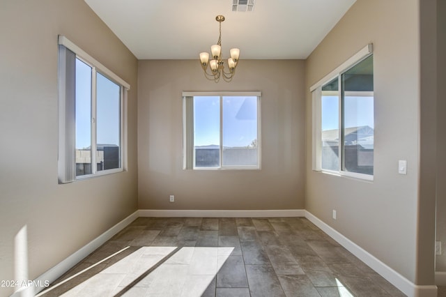 unfurnished room with a wealth of natural light and a chandelier