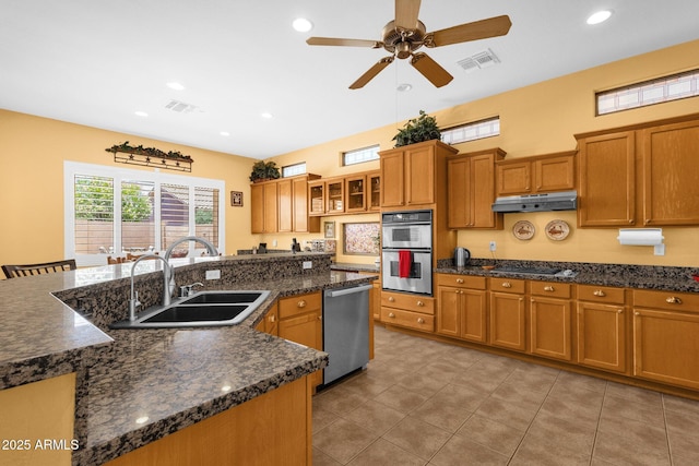 2069 E Winchester Way, Chandler, AZ 85286 - kitchen with stainless steel appliances, brown cabinetry, under cabinet range hood, light tile patterned floors, and ceiling fan