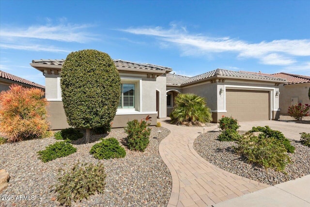 mediterranean / spanish-style home featuring a garage, driveway, a tile roof, and stucco siding