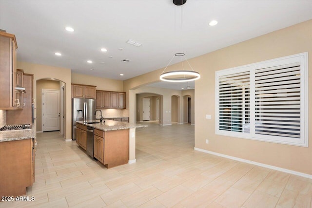 kitchen featuring arched walkways, open floor plan, a sink, and decorative light fixtures