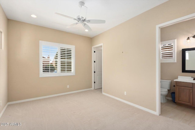 unfurnished bedroom with recessed lighting, baseboards, ensuite bathroom, and light colored carpet