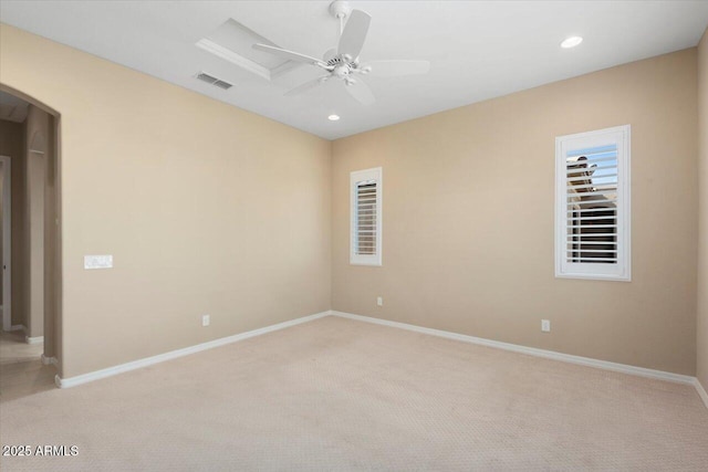 empty room featuring arched walkways, ceiling fan, recessed lighting, visible vents, and baseboards