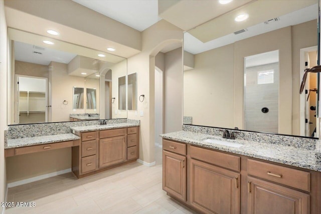 full bath with two vanities, visible vents, a sink, and walk in shower