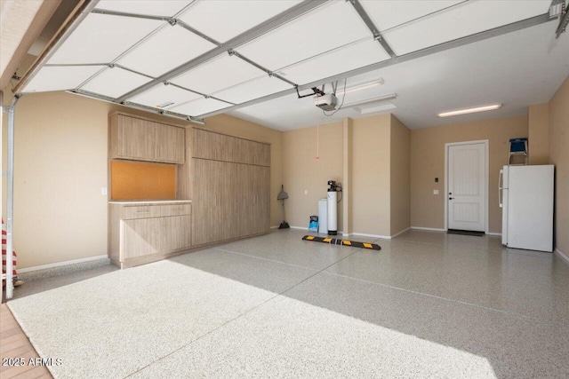 garage featuring a garage door opener, freestanding refrigerator, and baseboards