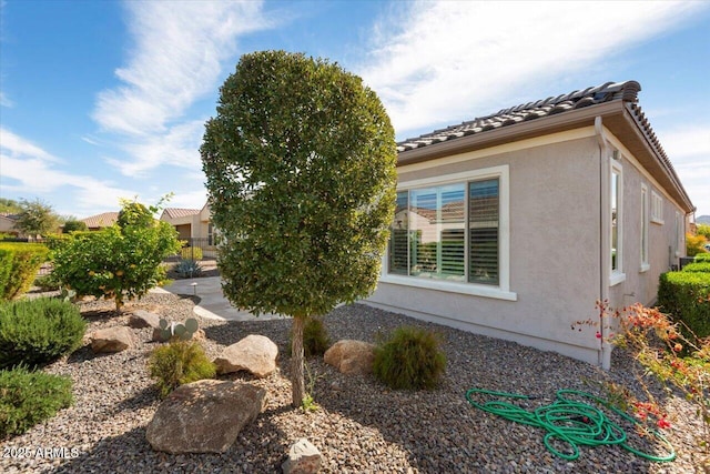 view of side of property featuring a tile roof and stucco siding