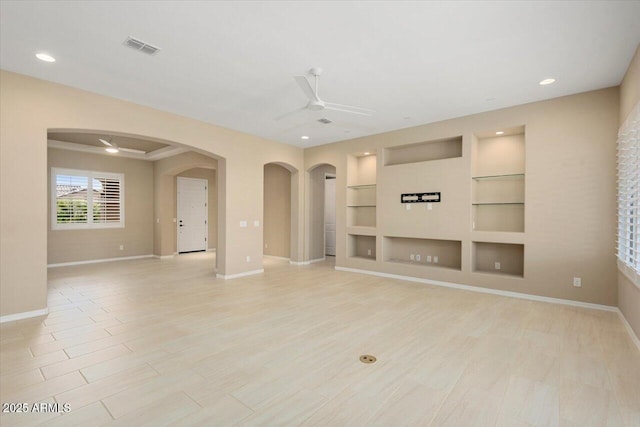 unfurnished living room with built in shelves, arched walkways, visible vents, and ceiling fan