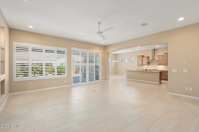 unfurnished living room with ceiling fan, baseboards, a sink, and recessed lighting