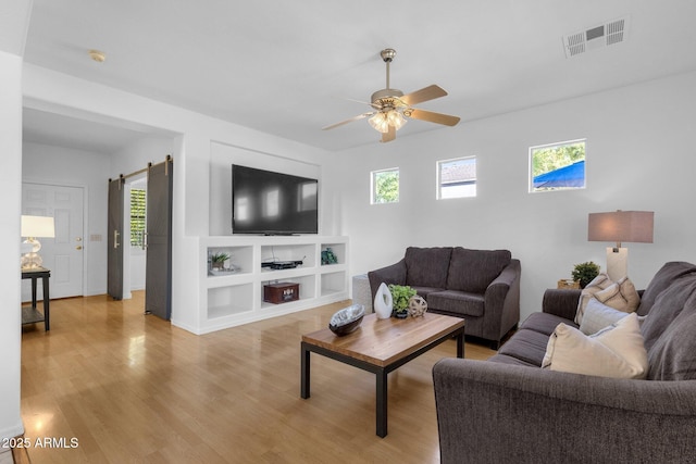 2545 E Harrison Ct, Gilbert, AZ 85295 - living area with healthy amount of natural light, ceiling fan, light wood finished floors, and a barn door