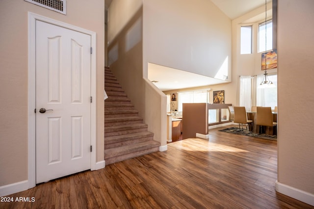 interior space with a healthy amount of sunlight, high vaulted ceiling, wood-type flooring, and a chandelier