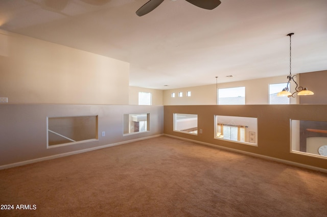 carpeted spare room featuring ceiling fan with notable chandelier