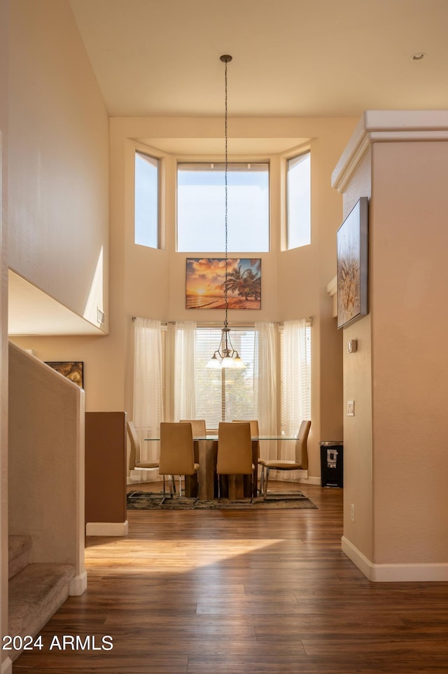 dining area with a towering ceiling, hardwood / wood-style floors, and a wealth of natural light