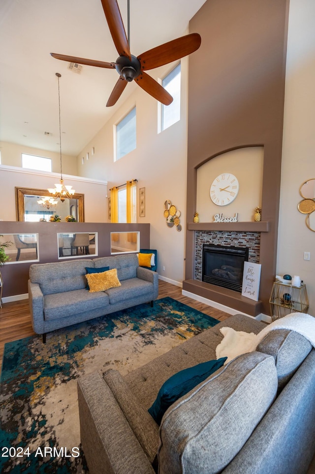 living room with a tile fireplace, hardwood / wood-style floors, ceiling fan with notable chandelier, and high vaulted ceiling