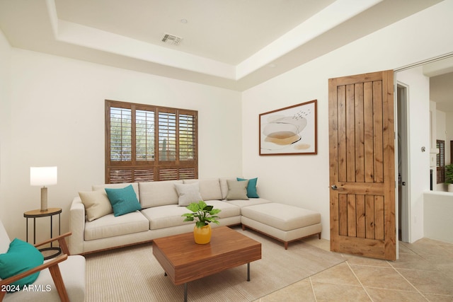 living room with light tile patterned floors and a tray ceiling