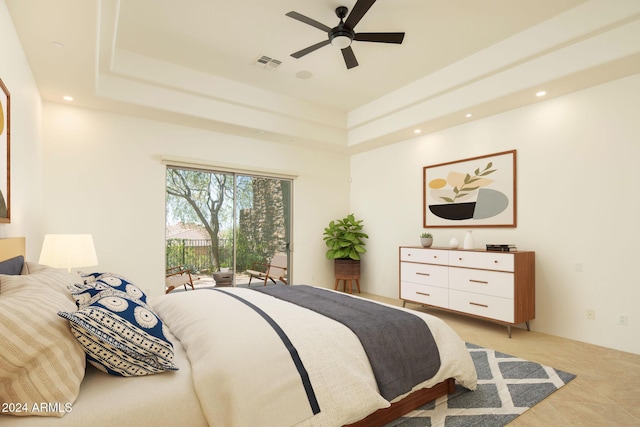 tiled bedroom featuring access to exterior, a tray ceiling, and ceiling fan