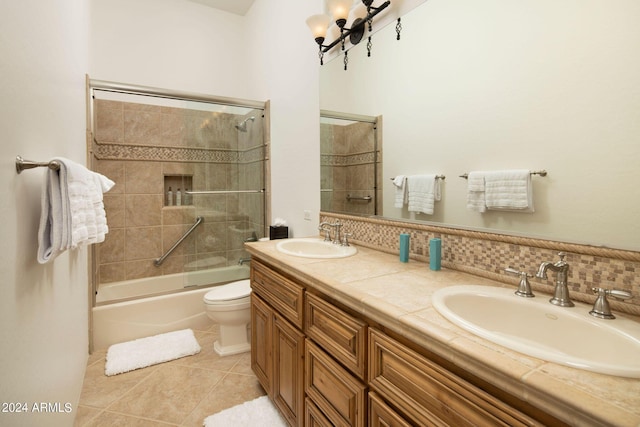 full bathroom featuring vanity, backsplash, tile patterned floors, bath / shower combo with glass door, and toilet