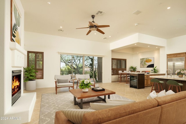 tiled living room featuring wine cooler, ceiling fan, and sink