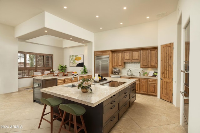 kitchen with a kitchen bar, stainless steel built in fridge, a spacious island, and sink