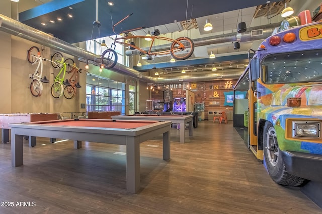 recreation room featuring wood-type flooring, a towering ceiling, and billiards