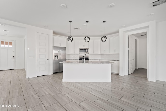 kitchen with white cabinetry, an island with sink, light stone countertops, and appliances with stainless steel finishes