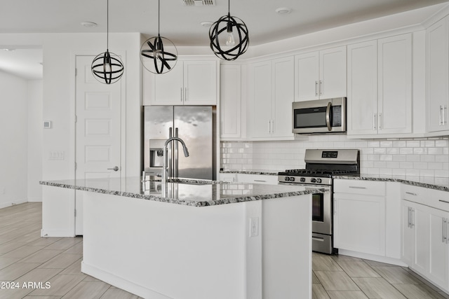 kitchen with white cabinets, stainless steel appliances, hanging light fixtures, and a center island with sink