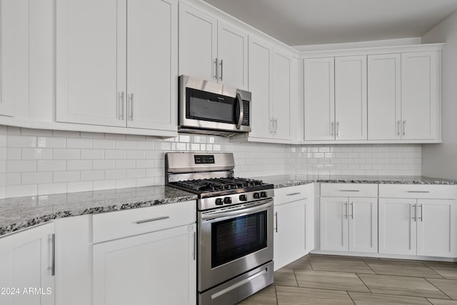 kitchen with white cabinets, decorative backsplash, light stone countertops, and stainless steel appliances