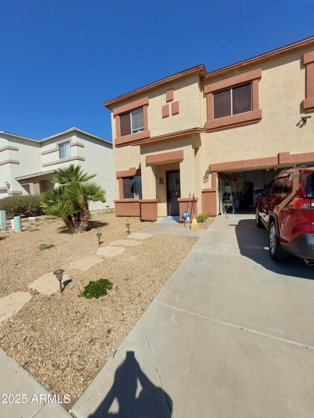 view of property featuring a garage, concrete driveway, and stucco siding