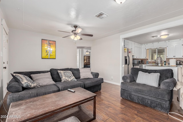 living room with ceiling fan and dark wood-type flooring