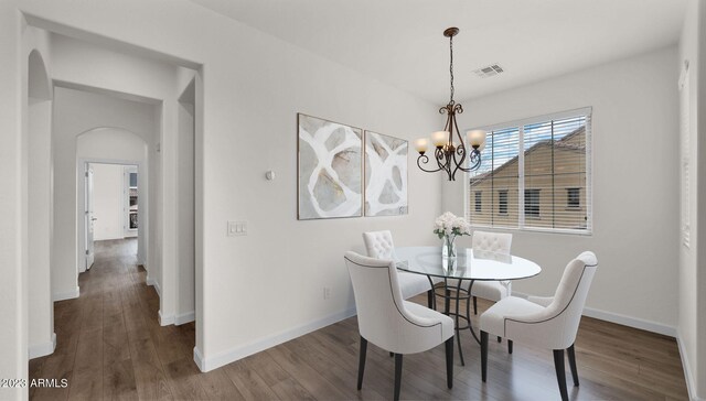 dining area featuring arched walkways, a notable chandelier, wood finished floors, visible vents, and baseboards