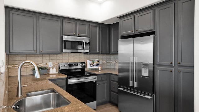 kitchen featuring sink, backsplash, stone countertops, and appliances with stainless steel finishes