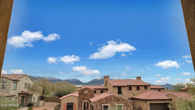 exterior space featuring a chimney, stucco siding, an attached garage, a mountain view, and a tiled roof