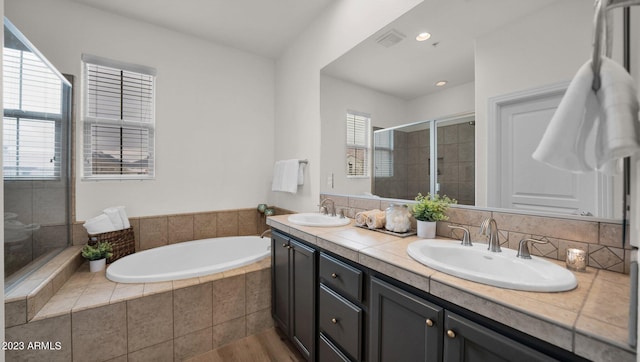 bathroom with hardwood / wood-style flooring, independent shower and bath, double sink vanity, and decorative backsplash