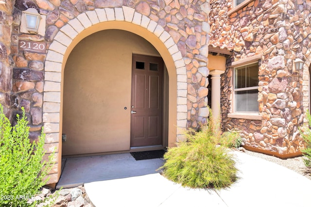 doorway to property with stone siding and stucco siding