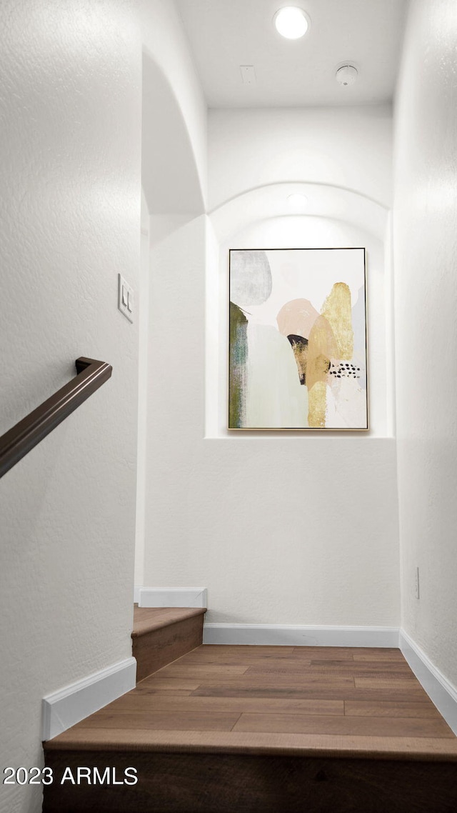 stairway with baseboards, wood finished floors, and recessed lighting