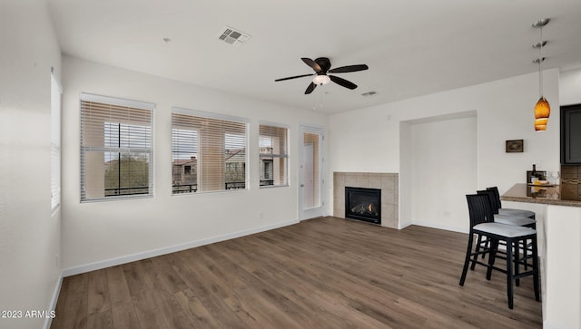 unfurnished living room with a fireplace, ceiling fan, and dark hardwood / wood-style floors